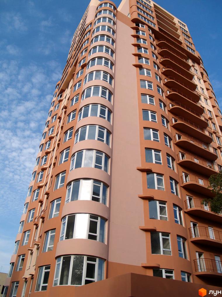 Житловий комплекс ЖК Фонтан з виглядом на фасад з великими вікнами та балконами. Прибудинкова територія озеленена та облаштована.