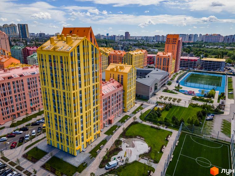 Житловий комплекс Комфорт Таун з яскравими будинками та облаштованою прибудинковою територією, включаючи спортивні майданчики.