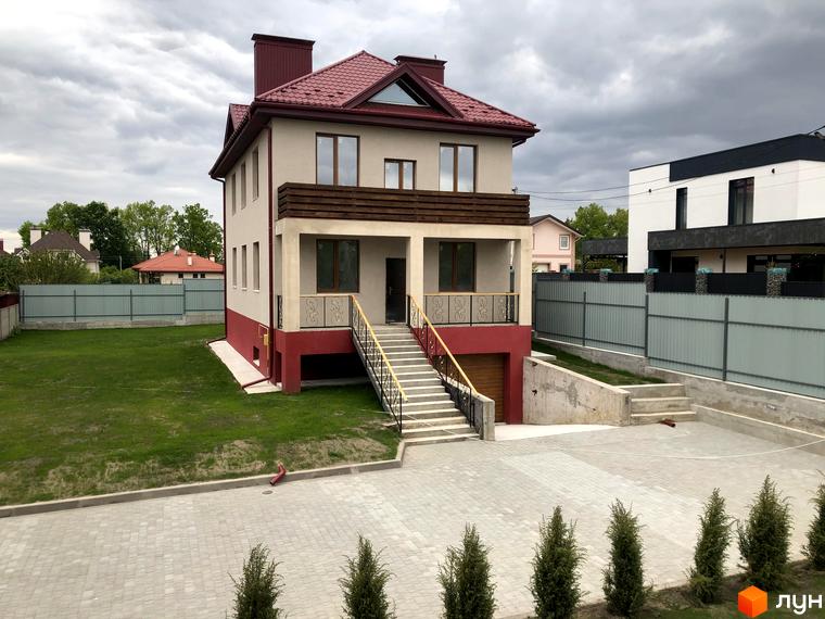 Котеджне містечко КМ Горобиновий маєток: двоповерховий будинок з червоним дахом та світлими стінами, огороджена територія з газоном та вимощеним подвір'ям.