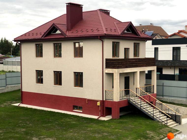Котеджне містечко КМ Горобиновий маєток: двоповерховий будинок з червоним дахом та балконом, зелена прибудинкова територія.
