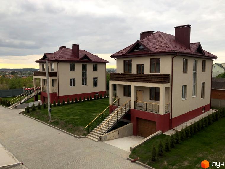 Зовнішній вигляд двоповерхових будинків котеджного містечка КМ Горобиновий маєток з червоними дахами та прибудинковою територією з газоном та сходами.