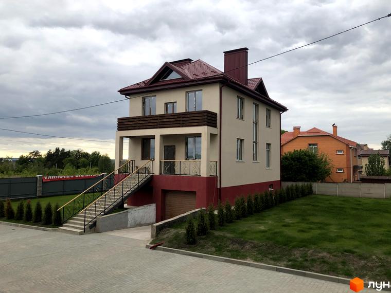 Котеджне містечко КМ Горобиновий маєток. Зовнішній вигляд двоповерхового будинку з балконом та сходами на прибудинкову територію з газоном та деревами.