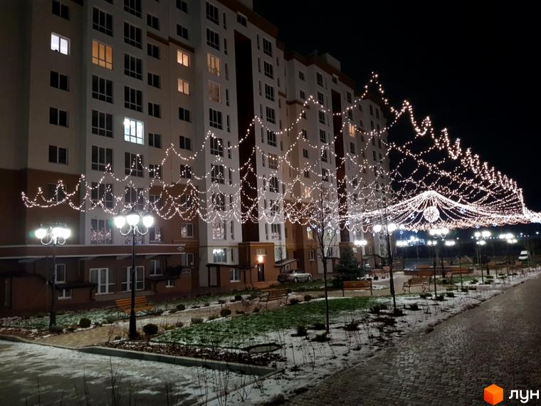 Житловий комплекс Львівський маєток вночі з святковою ілюмінацією. Зовнішній вигляд новобудови та прибудинкова територія з ліхтарями та лавками.