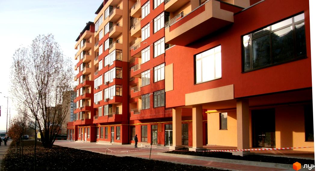 Зображення фасаду та прибудинкової території Житлового комплексу Академмістечко. Багатоповерховий будинок з великими вікнами та балконами.