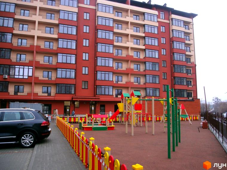 Зображення багатоповерхового будинку Житловий комплекс Академмістечко з дитячим майданчиком на прибудинковій території.