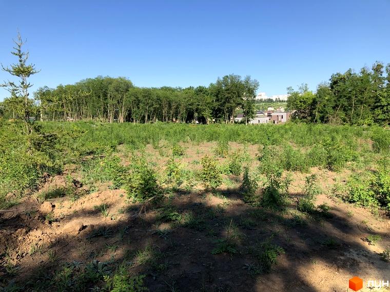 На зображенні територія майбутнього будівництва Котеджне містечко Шалє Грааль. Поруч зелені насадження та чисте небо.