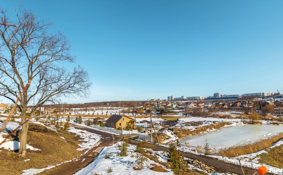 Котеджне містечко Шале Грааль. Дерев'яний будинок з панорамними вікнами, поруч доглянута територія, дорога та засніжені ділянки.