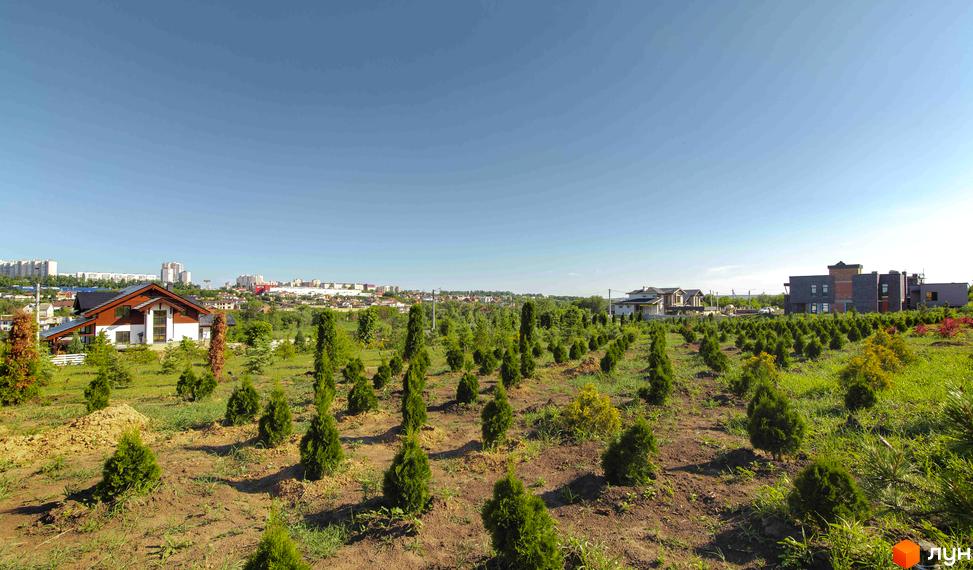 Зображення Котеджного містечка Шалє Грааль з будинками та доглянутою прибудинковою територією з деревами та газонами, що створює затишну атмосферу.