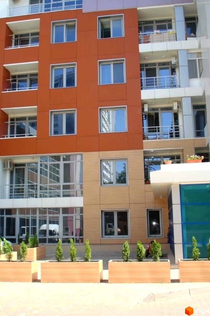 Житловий комплекс Сігурд Холл з яскравим фасадом та великими вікнами. Прибудинкова територія озеленена декоративними рослинами.