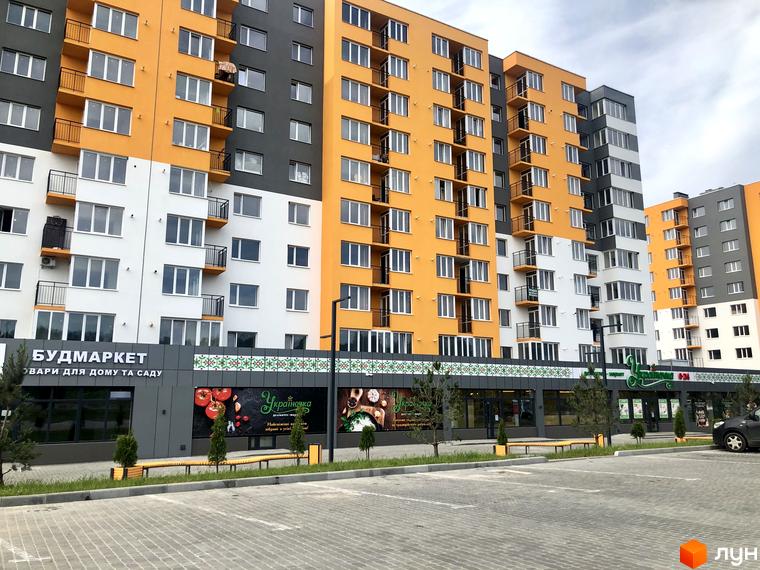 Житловий комплекс Сімейний COMFORT. Фасад будинку виконаний у помаранчевих, сірих та білих кольорах. Прибудинкова територія з парковкою та озелененням.