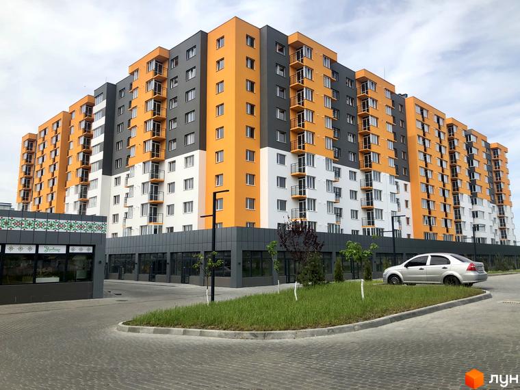 Житловий комплекс Сімейний COMFORT з яскравим фасадом та балконами. На прибудинковій території облаштований паркінг та зелені зони.