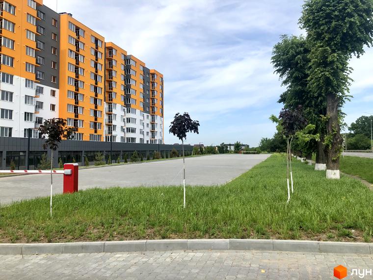 Житловий комплекс Сімейний COMFORT з яскравим фасадом та доглянутою прибудинковою територією з зеленими насадженнями та парковкою.