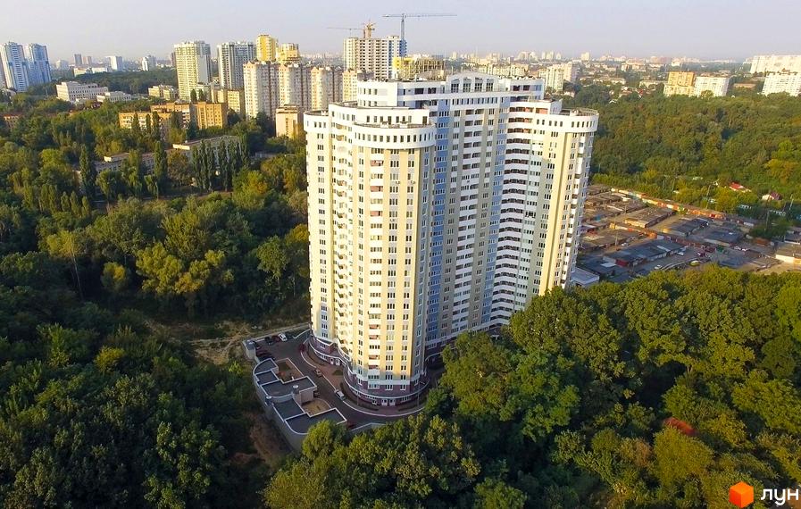 ЖК Сирецький Бояр. Висотна будівля з численними вікнами розташована серед зелених насаджень. На території комплексу є парковка.