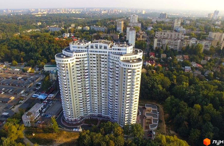 Висотна будівля ЖК Сирецький Бояр на тлі міської забудови. На території комплексу є парковка та зелені насадження.