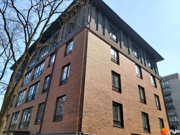 Новобудова ЖК Brighton Residence з цегляним фасадом та великими вікнами. Навколо будинку ростуть дерева.