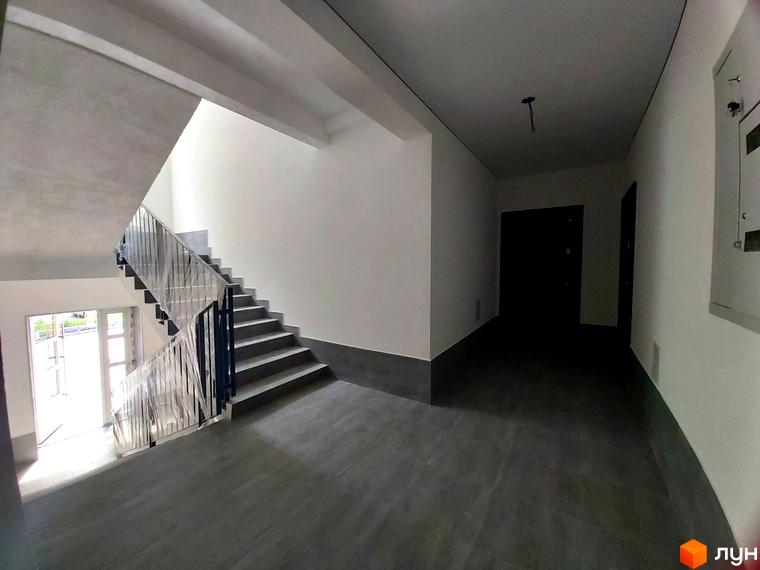 Просторий під'їзд з сходами та дверима в ЖК Brighton Residence. Сучасний дизайн та функціональне планування створюють комфортне середовище для мешканців.