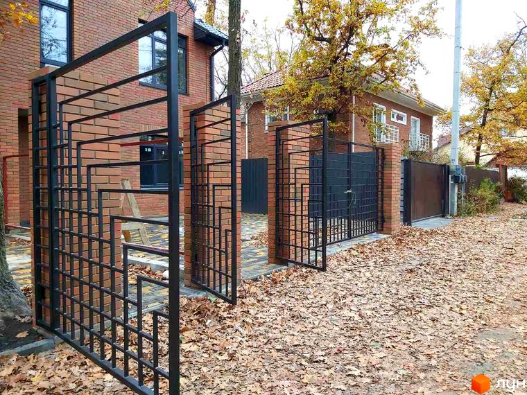 Таунхауси Brighton-park: цегляний будинок з металевою огорожею та кованими воротами. Прибудинкова територія встелена опалим листям.