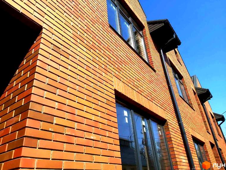 Цегляний будинок таунхаусів Brighton 3 з великими вікнами на тлі блакитного неба. Видно фасад будівлі з декоративними елементами.