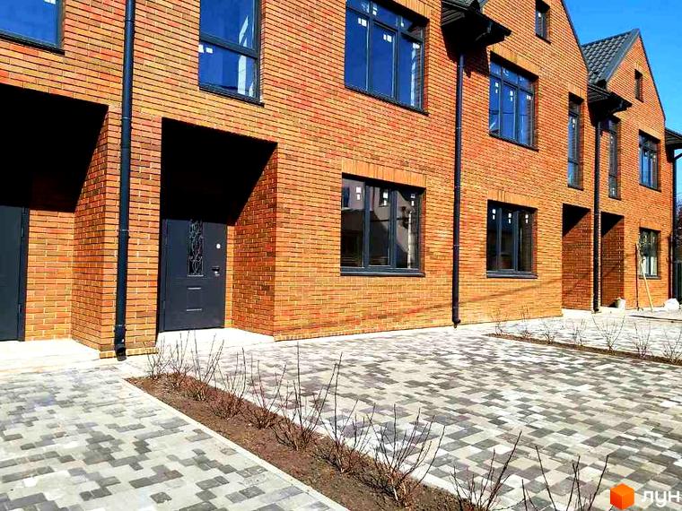 Фасад таунхаусів Brighton 3 з червоної цегли та брукована прибудинкова територія. Зовнішній вигляд новобудови та її територія.