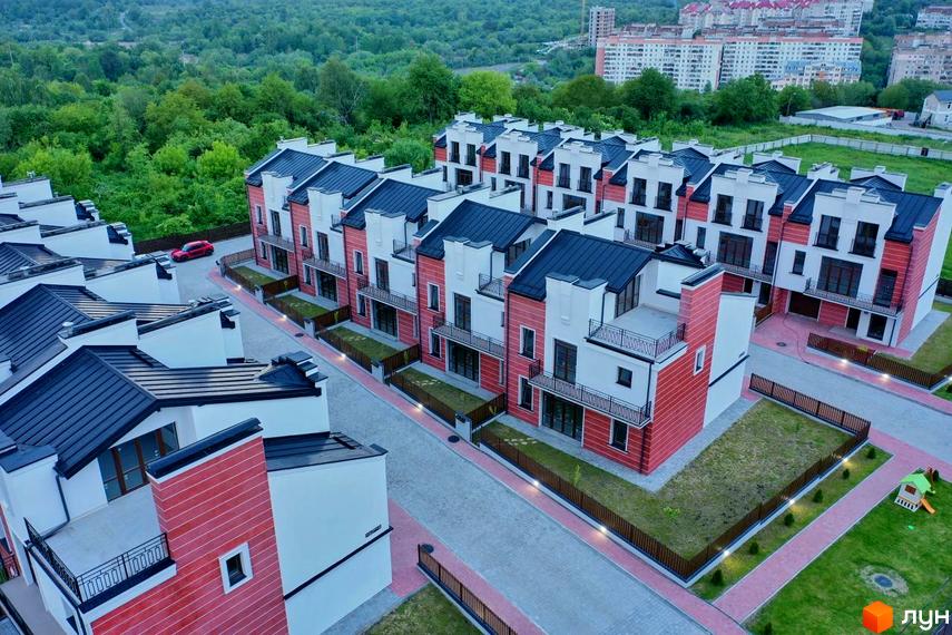 Зображення таунхаусів у Котеджному містечку Raytman Park. Вигляд на фасади будинків з чорними дахами та червоно-білим оздобленням, облаштована прибудинкова територія.