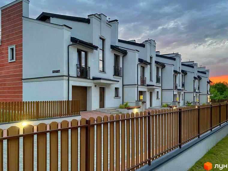 Зображення таунхаусів у Raytman Park. Вигляд будинків з коричневими парканами та освітленням на прибудинковій території.