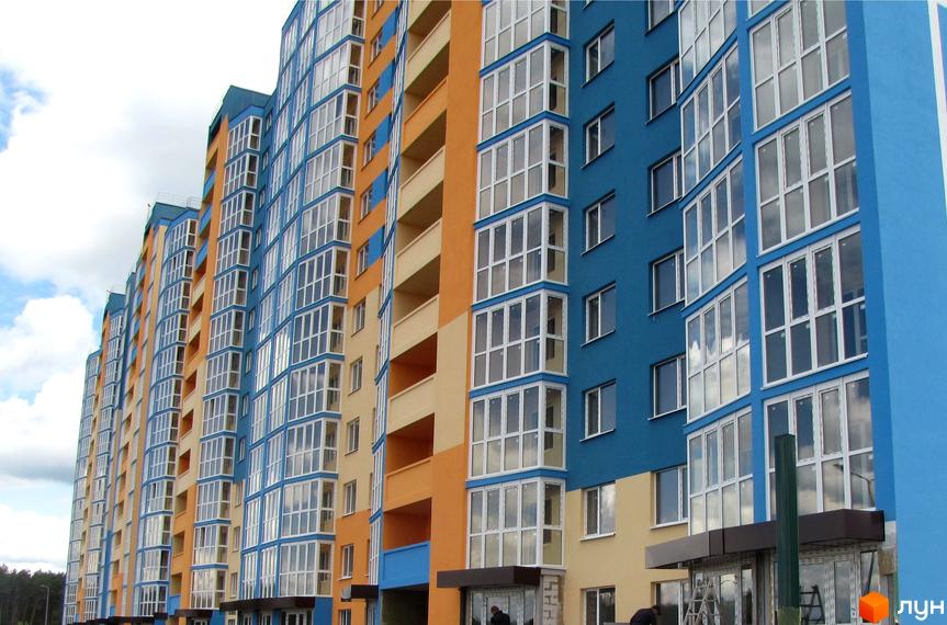 Багатоповерхові будинки житлового комплексу LaLaLand з синіми та помаранчевими фасадами, великими вікнами та заскленими балконами. Навколо видно зелені насадження.