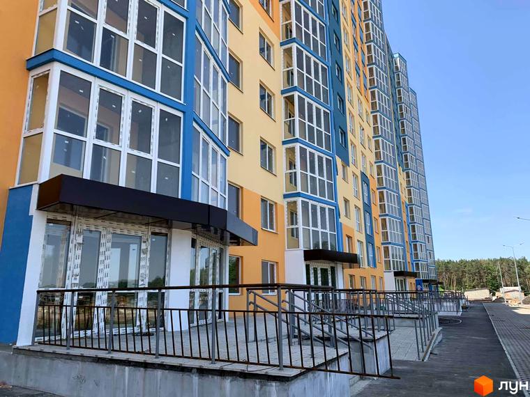 Багатоповерховий будинок ЖК LaLaLand з панорамними вікнами та яскравим фасадом. На передньому плані – вхідна група з козирком та огородженням, поруч – тротуар.