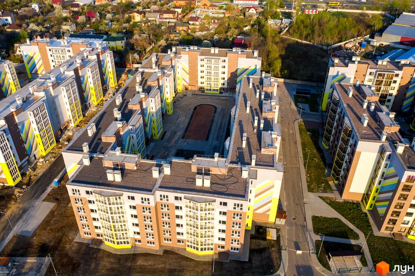 Вид зверху на житловий комплекс Welcome Home на Стеценка. Будинки мають коричнево-білий фасад з яскравими жовтими та блакитними елементами. На території комплексу є зелені зони та доріжки.