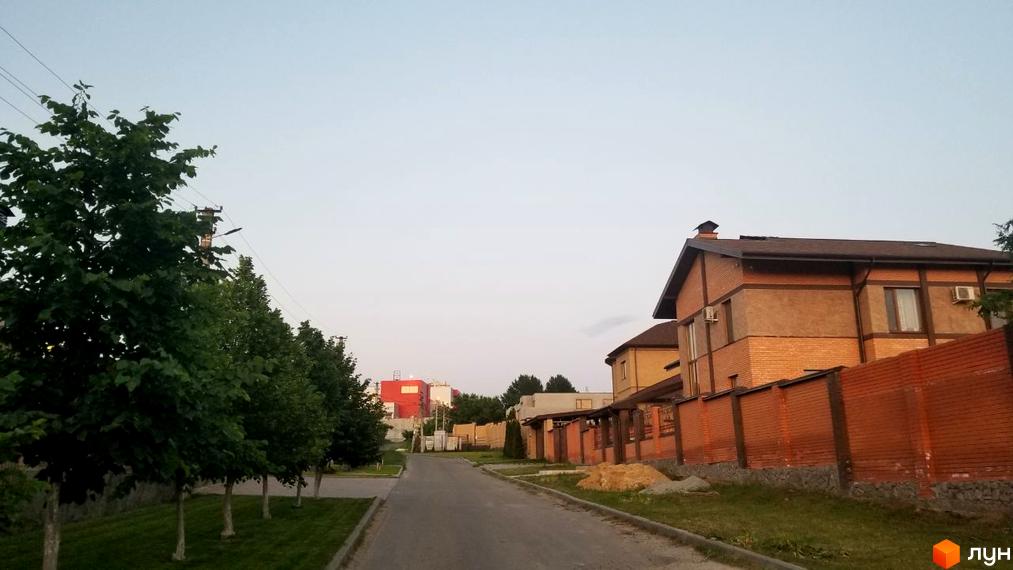 Зображення вулиці в Котеджному містечку Флоринка. Двоповерхові будинки з цегляними парканами вздовж дороги.