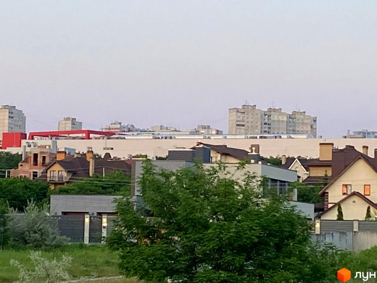 Фото будівель Комплексу Флоринка з зеленими насадженнями на передньому плані. Вигляд на житловий район та міську забудову.