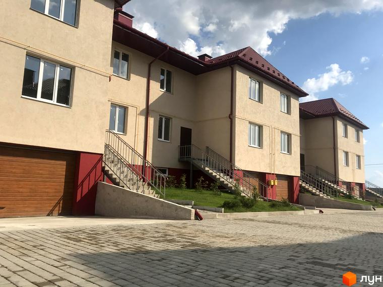 Котеджне містечко КМ Горобиновий маєток: фасади будівель з червоними дахами та прибудинкова територія з бруківкою.
