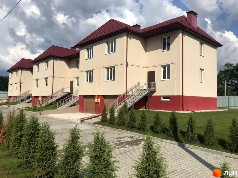 Зовнішній вигляд Котеджного містечка Горобиновий маєток: двоповерхові будинки з червоними дахами та сходами до входу, зелена територія.