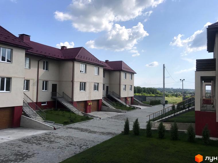Котеджне містечко Горобиновий маєток: двоповерхові котеджі зі світлими стінами, бордовими дахами, доріжками з бруківки та зеленими газонами.