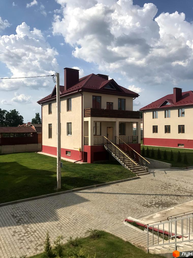 Зображення будинку в Котеджному містечку Горобиновий маєток. На фото видно будинок з червоним дахом та зелений газон.