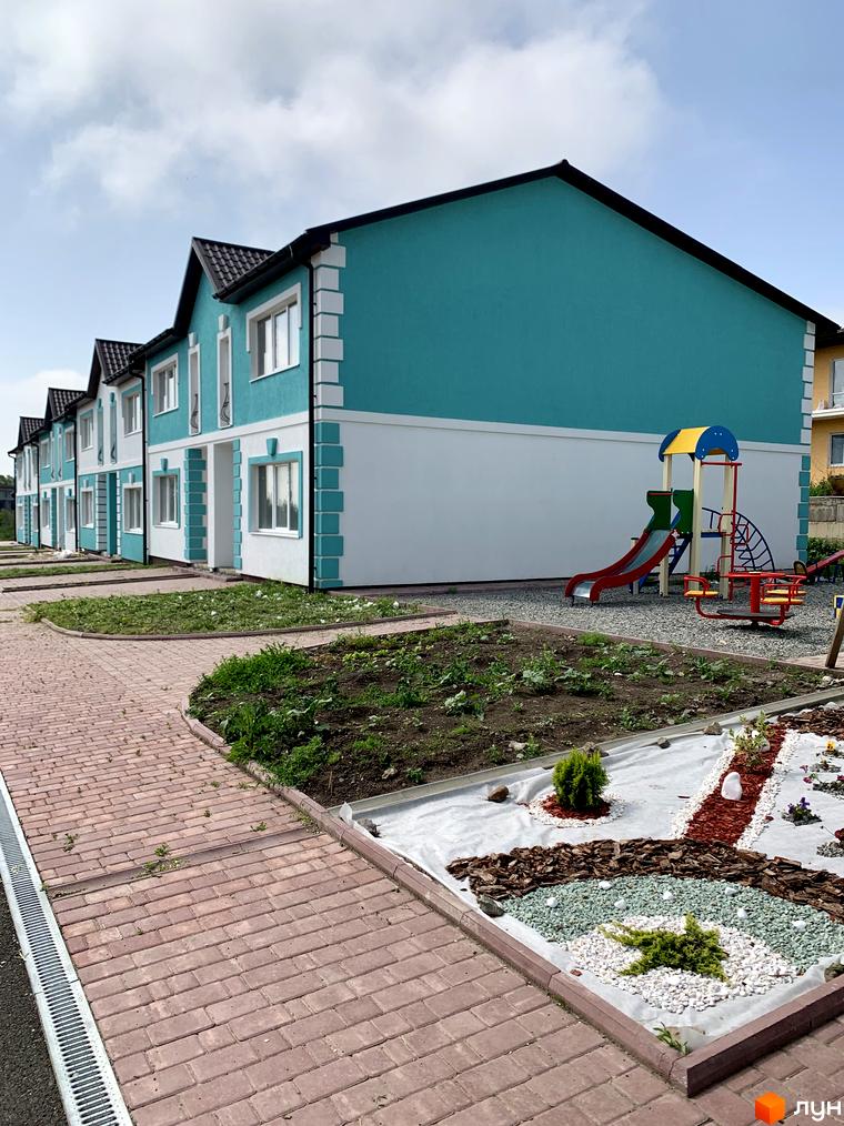 Зовнішній вигляд таунхаусів «Молодіжний XXI». Двоповерхові будинки з біло-бірюзовими фасадами та доглянутою прибудинковою територією.