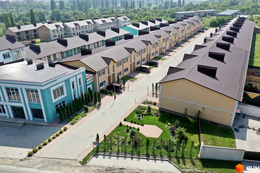 Зображення таунхаусів «Молодіжний XXI». Вигляд на фасади будинків з коричневими дахами та прибудинкову територію з газонами.