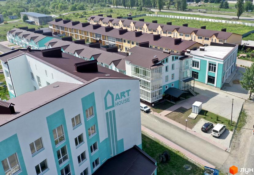 Фото таунхаусів «Молодіжний XXI» з виглядом на фасади будинків з коричневими дахами та прибудинкову територію з дорогою.