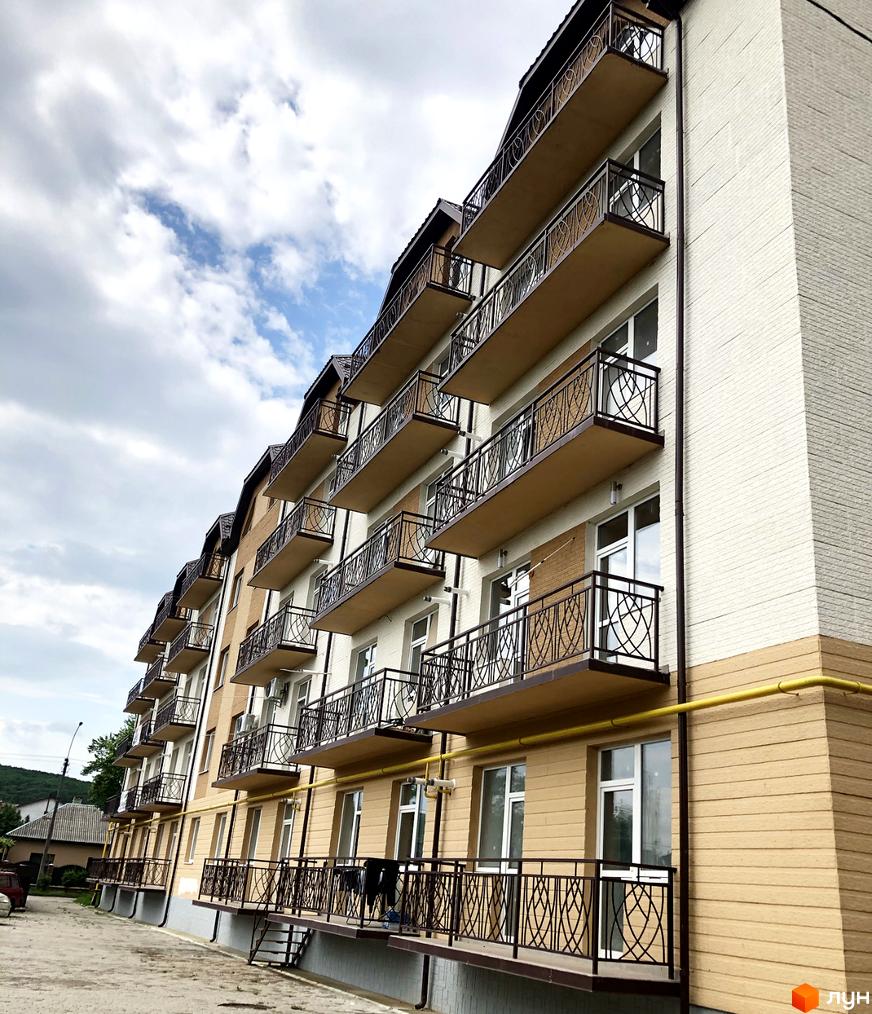 Зовнішній вигляд житлового комплексу Котляревського з численними балконами та вікнами. Будинок має цегляний фасад та коричневі елементи оздоблення.