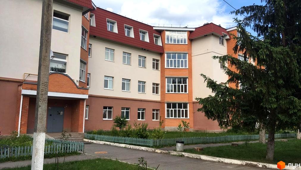 Зовнішній вигляд новобудови на вул. Гайок, 224б, з цегляними елементами та зеленим огородженням прибудинкової території.