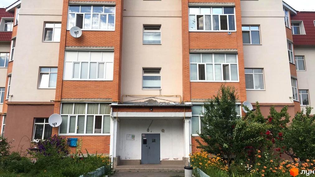 Багатоповерховий будинок на вул. Гайок, 224б з цегляними та світлими фасадами, білими вікнами. Озеленена прибудинкова територія з квітами.