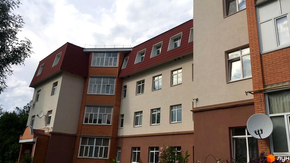 Фасад житлового комплексу на вулиці Гайок, 224б, з цегляними та штукатуреними елементами, червоним дахом та численними вікнами.