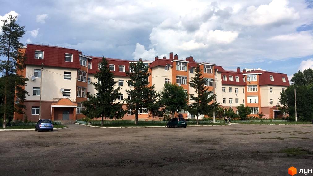 Зовнішній вигляд житлового комплексу на вулиці Гайок, 224б, з прибудинковою територією та автомобілями. Багатоповерховий будинок з червоним дахом та світлими стінами.