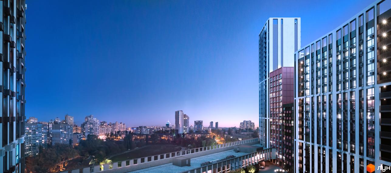 Житловий комплекс Старт з висотними будинками та освітленими вікнами на тлі вечірнього міста. Видно прибудинкову територію з зеленими насадженнями та міст-перехід.