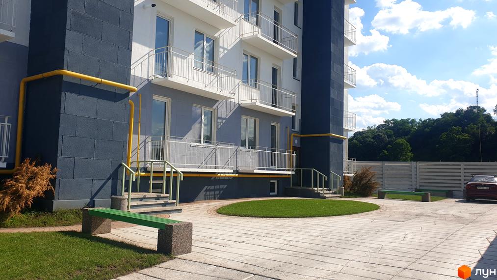 Житловий комплекс Дмитро-Олександрівський: фасади будівель з балконами та вікнами, прибудинкова територія з газоном та лавками.
