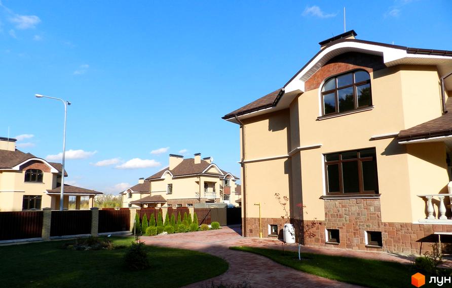 Зображення Котеджного містечка FEOFANIA COTTAGE: двоповерхові будинки з коричневими дахами та вікнами, доглянута прибудинкова територія з газоном та доріжками.