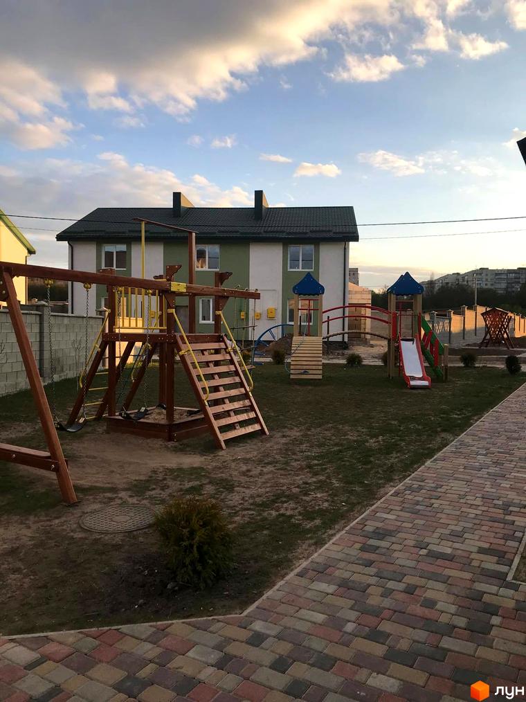 Житловий комплекс «Сонячна Долина»: будинок з зеленим дахом та дитячий майданчик на території. Бруківка на доріжках та газон навколо.