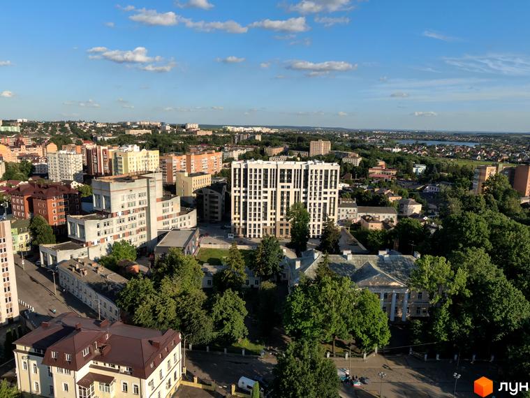 Вид на ЖК Prestige Apartments з висоти пташиного польоту. Багатоповерховий будинок з білими фасадами та прибудинкова територія з деревами.
