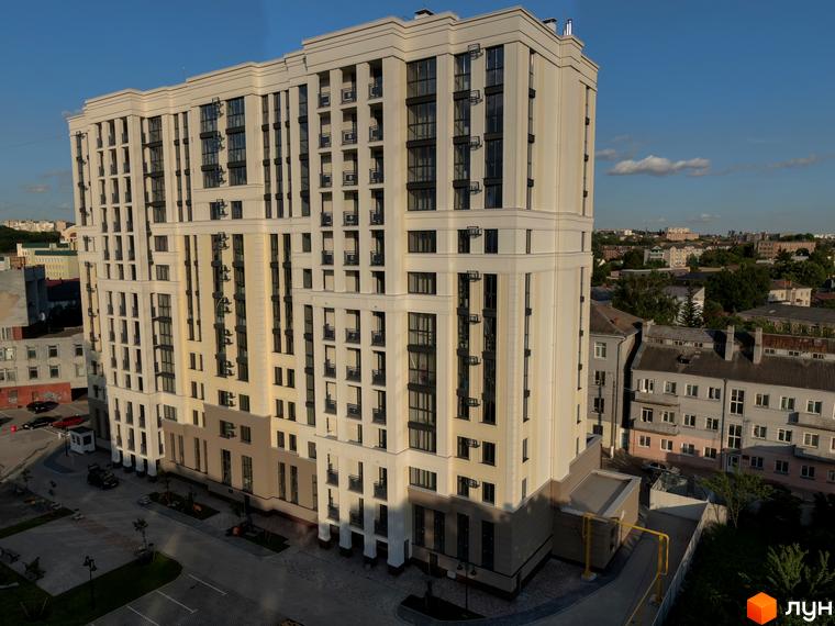 Висотна будівля ЖК Prestige Apartments з великою кількістю вікон та балконів. На прибудинковій території є парковка та зелені насадження.