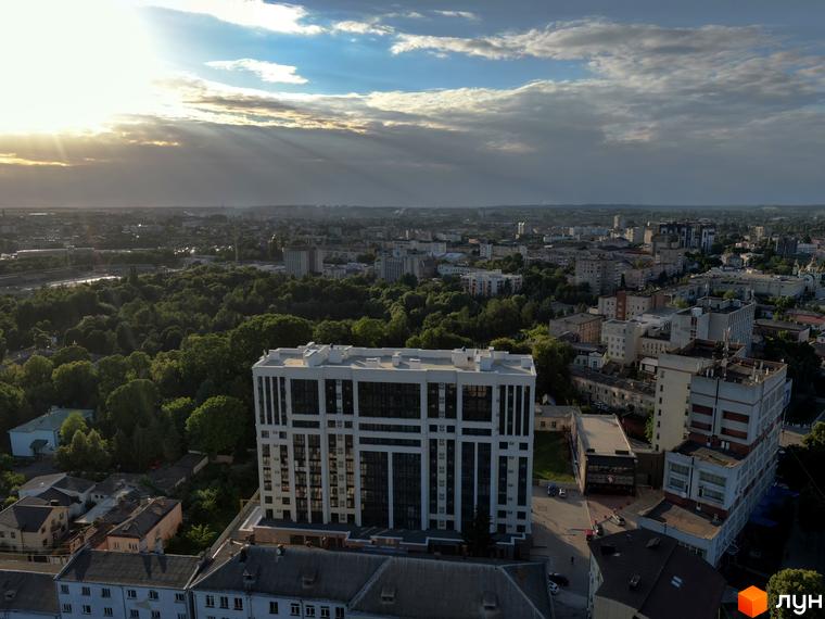 Висотна будівля ЖК Prestige Apartments на фоні міського пейзажу. Архітектура з великою кількістю вікон, навколо зелені насадження.
