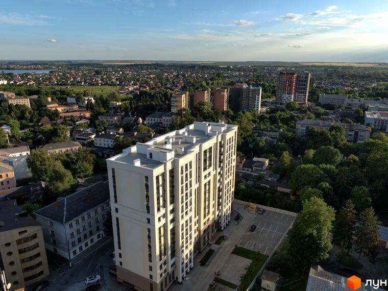 Висотна будівля ЖК Prestige Apartments з великою кількістю вікон. На території є парковка та зелені насадження.